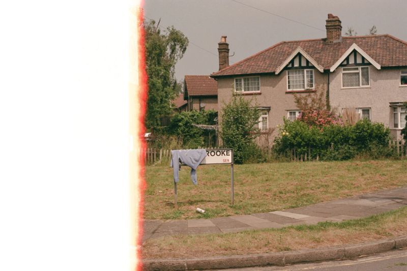 Still photo of a road, half the frame obscured by a light leak